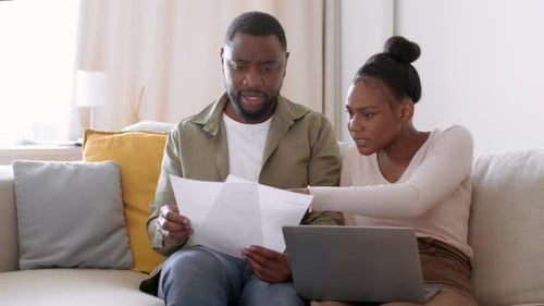 Couple Reviewing Financials on Couch with Laptop