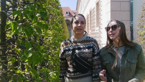Two young women stroll through lush garden