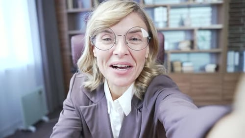 POV Close up. Smiling mature businesswoman talking on online video call holding smartphone and look