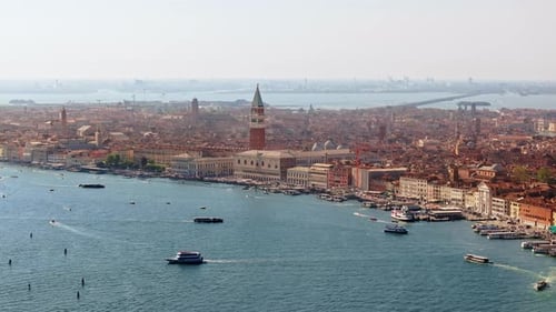 Aerial drone view of boats moving near St. Mark's Square in Venice Italy, with the city on the backg