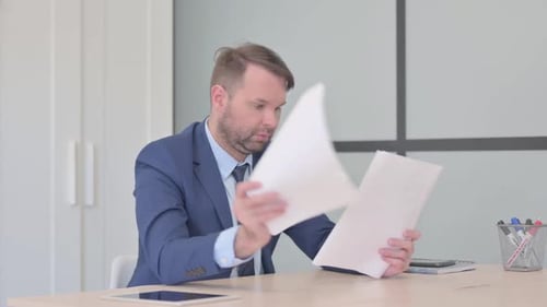 Professional Man Reads Documents at Office Desk