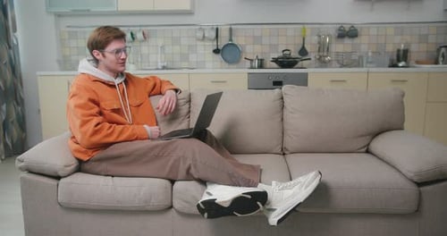 Young Adult On Laptop Video Call On Couch