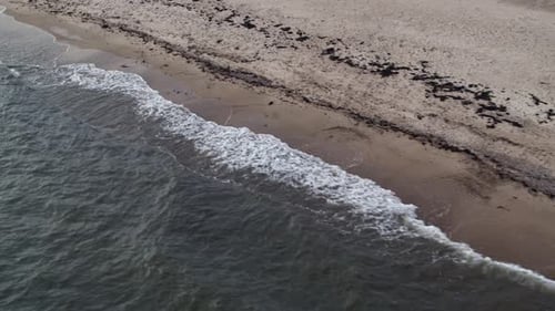 Seitlicher Drohnenflug über das Meer mit Blick auf den Sandstrand mit Wellen