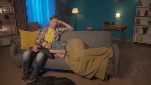 A Married Couple Sleeps in Front of the TV A Man with a Remote Control in His Hands Fell Asleep