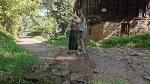 Un petit ami gentleman aide une fille à traverser le ruisseau pittoresque d'un village, geste romantique