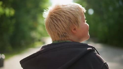 Boy with Blonde Hair Walking Away in Park