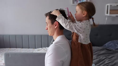 Child Combs Father's Hair in Bedroom at Home