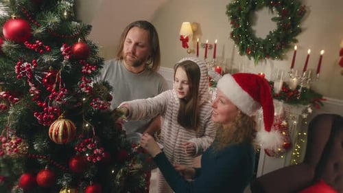 Family Decorates Christmas Tree with Red Ornaments