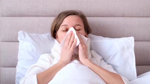 Sick Day at Home A Young Woman Has a Runny Nose and a Common Cold Sneezing Into Tissues