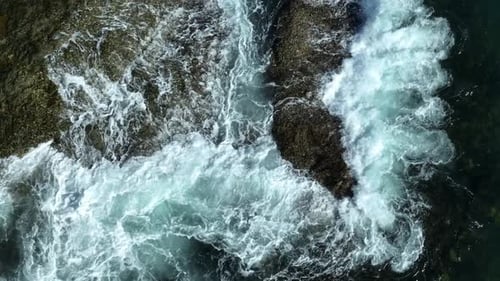 Rough ocean waves splashing against rocky shore.