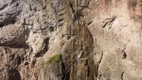 alpine waterfall on rocky wall, aerial close up shot