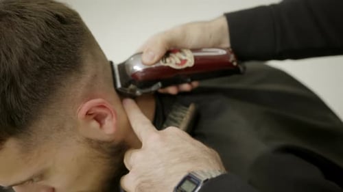 Friseur gibt einem Kunden einen Haarschnitt mit einem elektrischen Haarschneideclip