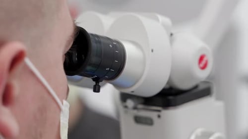 Scientist Looking Through Microscope in Lab