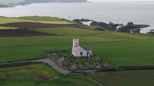 Approaching Pan Down of Coastal Northern Ireland Church with Cliffs and Atlantic Ocean
