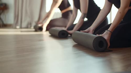 Women Unrolling Yoga Mats Before Class