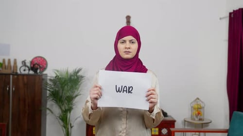 Muslimische Frau im Hijab-Schal steht mit Kriegsplakat