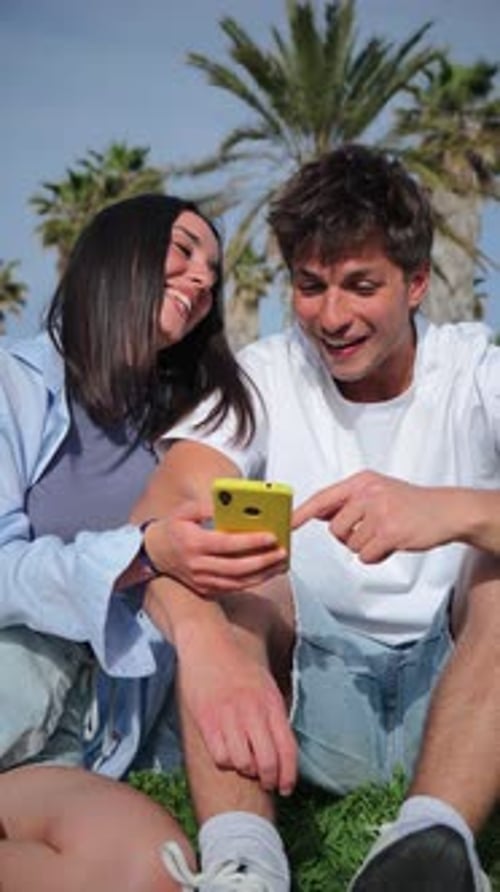 Young Couple Relaxing Outdoors with Smartphone