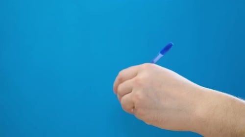 Hand with Blue Pen on Blue Background