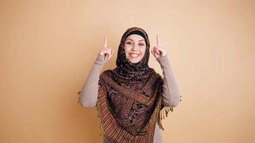 Young Muslim Woman in Hijab Pointing Up Happily