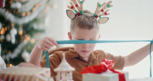 Boy Helps Man Wrap Christmas Presents at Home