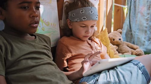 Two Children Play Together On Tablet Indoors