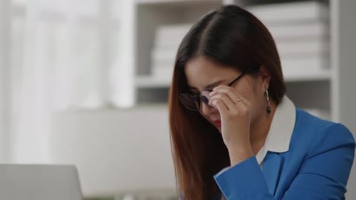 Businesswoman is seriously stressed working feel eye ache headache due to office syndrome.