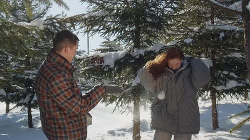 Vidéo dans laquelle un gars et une fille jettent de la neige en se promenant dans le parc d'hiver Un jeune homme heureux