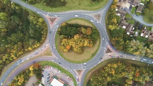 Aerial traffic rotating above urban roundabout traffic top down view