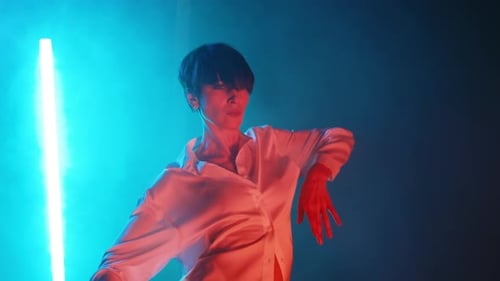 Talentosa mujer madura bailando movimientos de baile de estilo libre sobre fondo de neón azul en un artista de estudio