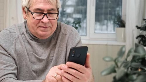 Man Reads Smartphone Indoors Near Window