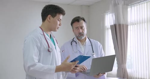 Two Doctors Reviewing Patient Data on Laptop