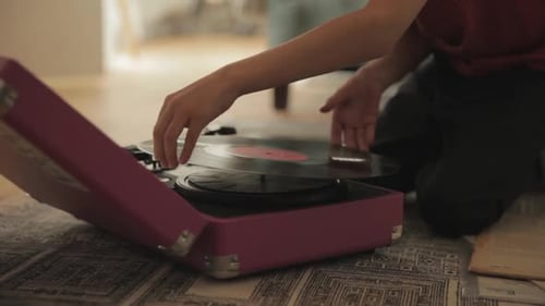 Child Places Record On Vintage Pink Record Player