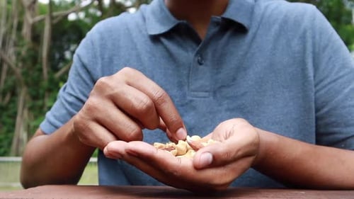 Young Men Eating Mux Nut Sitting on Park