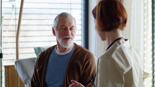 Female Doctor Examining Senior Patient in Bed in Hospital