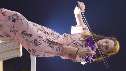 Woman in Dress Plays Electric Violin on Books
