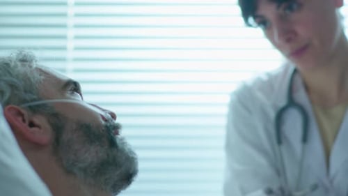 Sick Man and Careful Female Doctor Talking in Hospital Ward