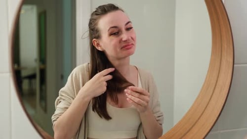 Young Woman Critically Examining Her Hair in Mirror