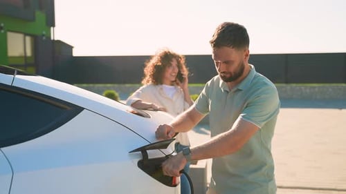 Young Couple Charging Their Modern Electric Car at Home