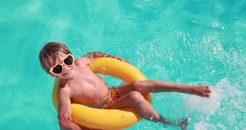 Smiling Boy Floating in Swimming Pool on Inner Tube