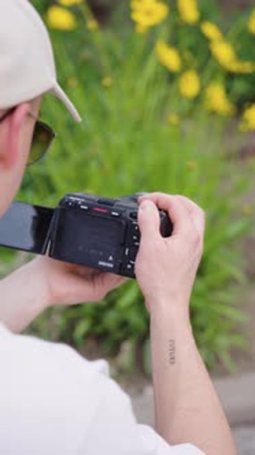 Vertical over shoulder view of videographer film blooming flowers, Czechia