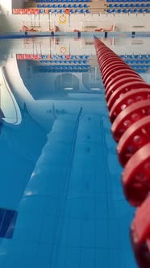 Ein Hallenbad mit kristallklarem Wasser und einem roten Spurteiler, der den Blick auf die