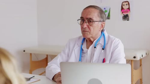 Pediatrician Talking with Mother and Child Girl at Doctor's Office