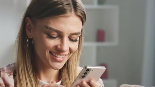 Woman Using Smartphone and Smiling Indoors