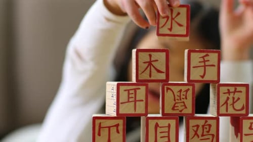 Child Stacking Wooden Blocks with Chinese Characters