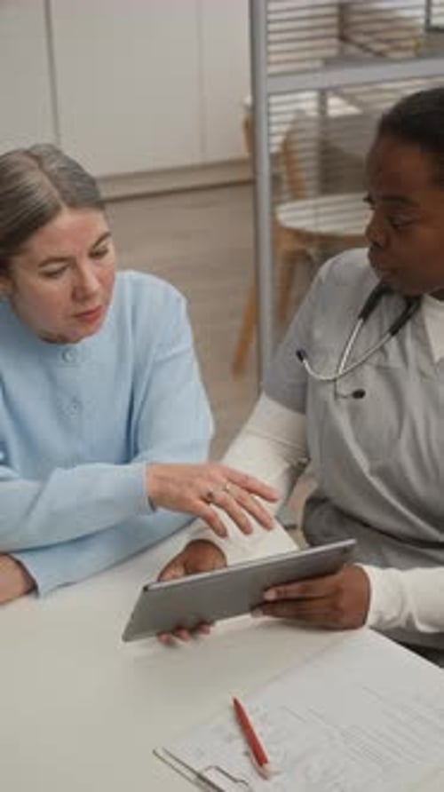 Woman Doctor Explains Info on Tablet to Patient
