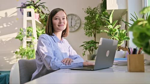 Young Woman Using Laptop at Home Office Desk