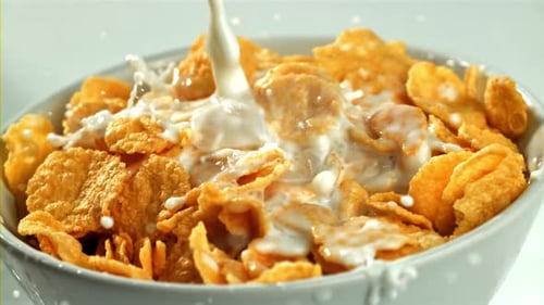 Milk Pouring Into Bowl of Golden Corn Flakes