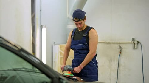 Handsome Car Service Worker with Muscular Body Polishing Car in Auto Repair Shop Using with Orbital