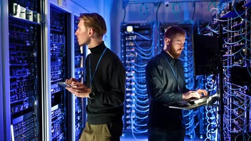 Two men programming in a server room