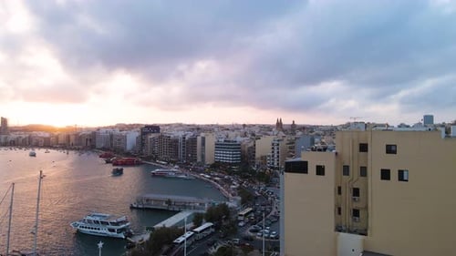 Expansive aerial panorama of Sliema's densely packed waterfront district at sunset, with dramatic